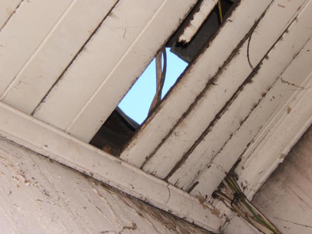 The sky is visible through a roof in disrepair