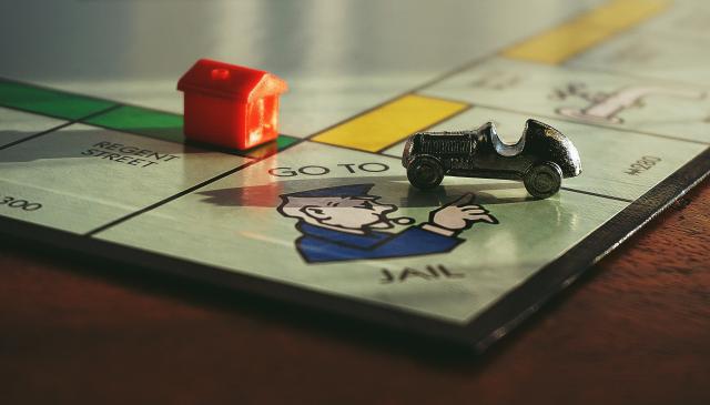 monopoly board game with car playing piece on the 'go to jail' square.