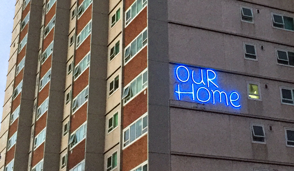 Tall apartment building with 'Our home' on the side