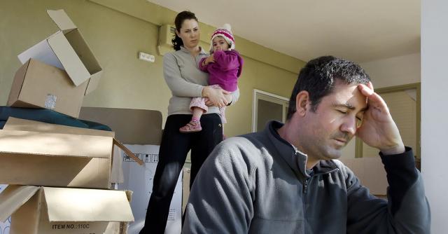 A woman, man and child, looking stressed, surrounded by moving boxes