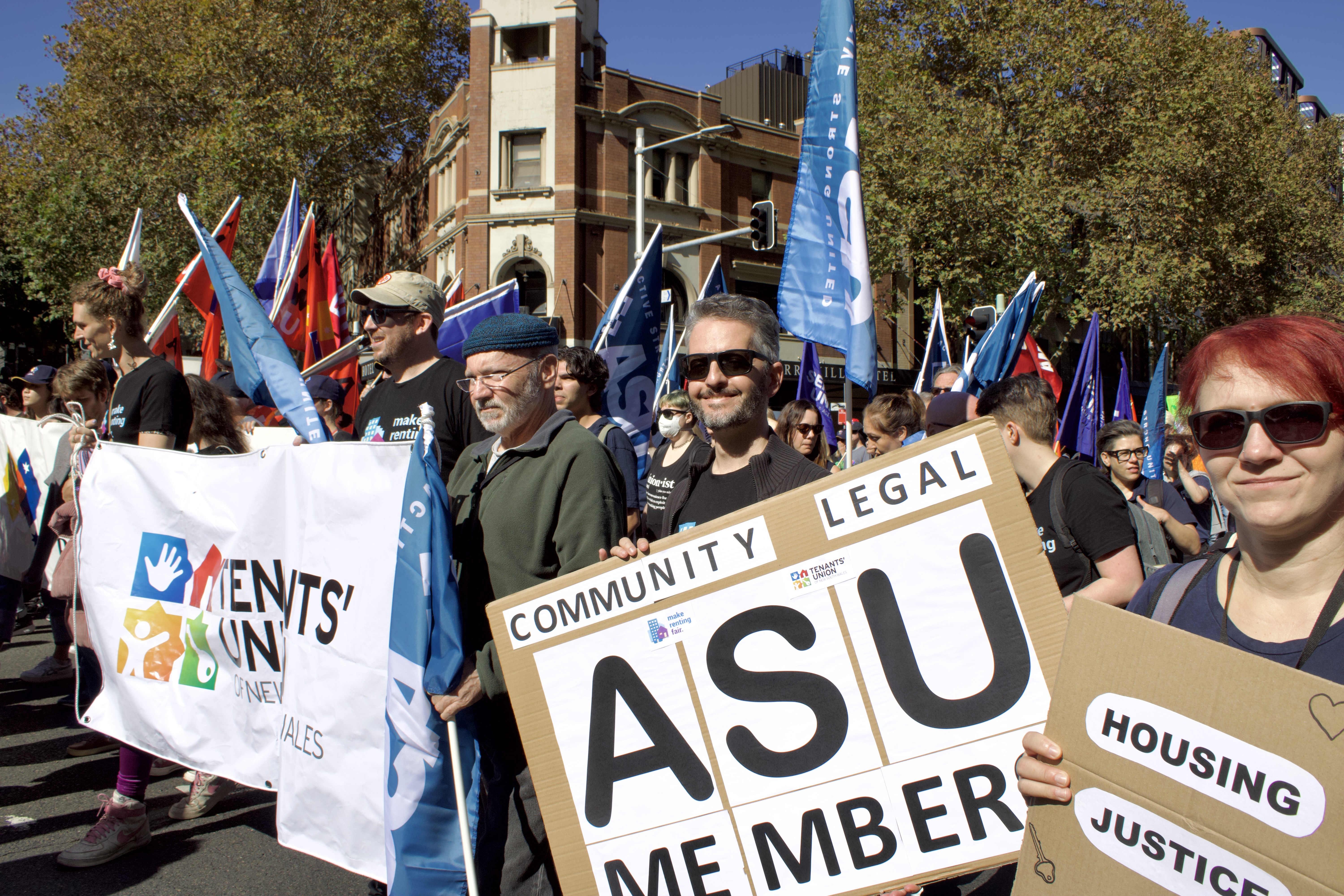 Tenants' Union staff members holding placards and marching. One placard reads Community Legal Members ASU (Australian Services Union).