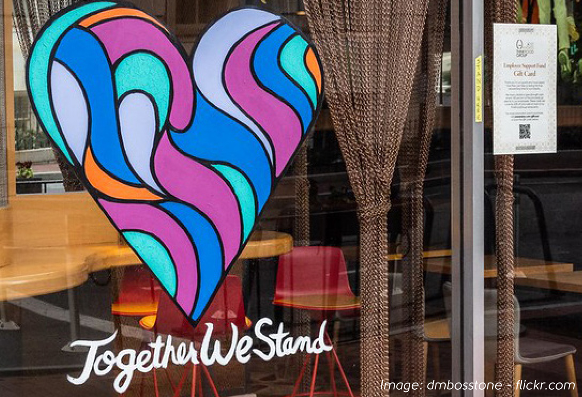 Colourful heart motif on cafe window with text Together We Stand underneath
