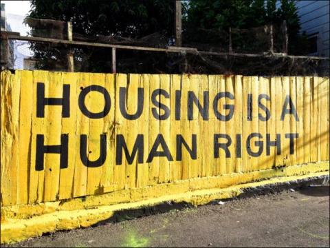 Housing is a human right painted on yellow wall in public street